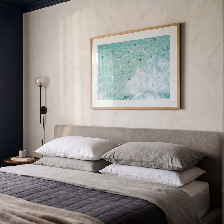 Framed Bondi Beach surfers print above a bed in a bedroom
