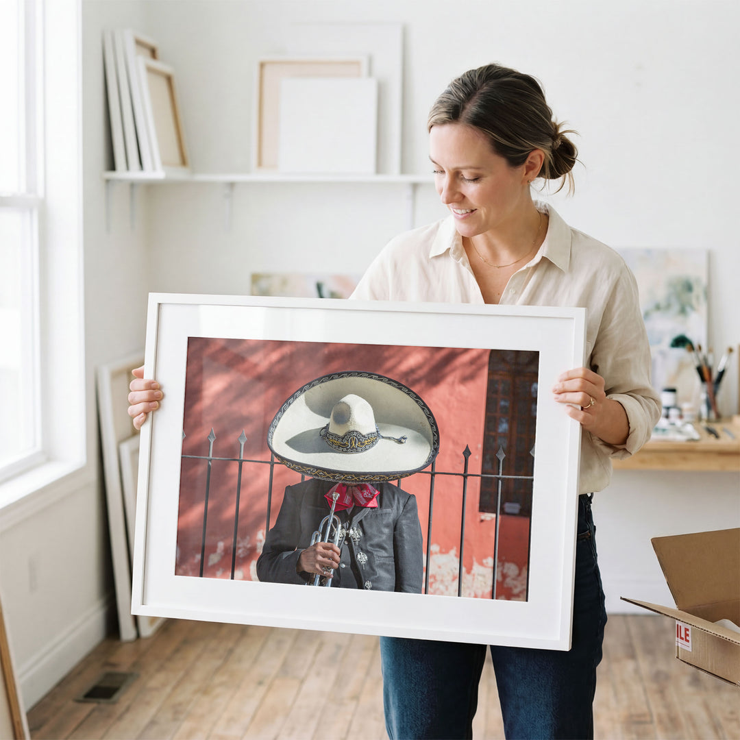 Woman holding a framed Mexican charro print in a studio