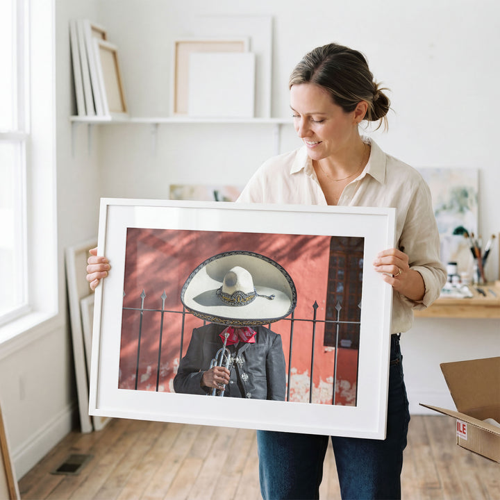 Woman holding a framed Mexican charro print in a studio