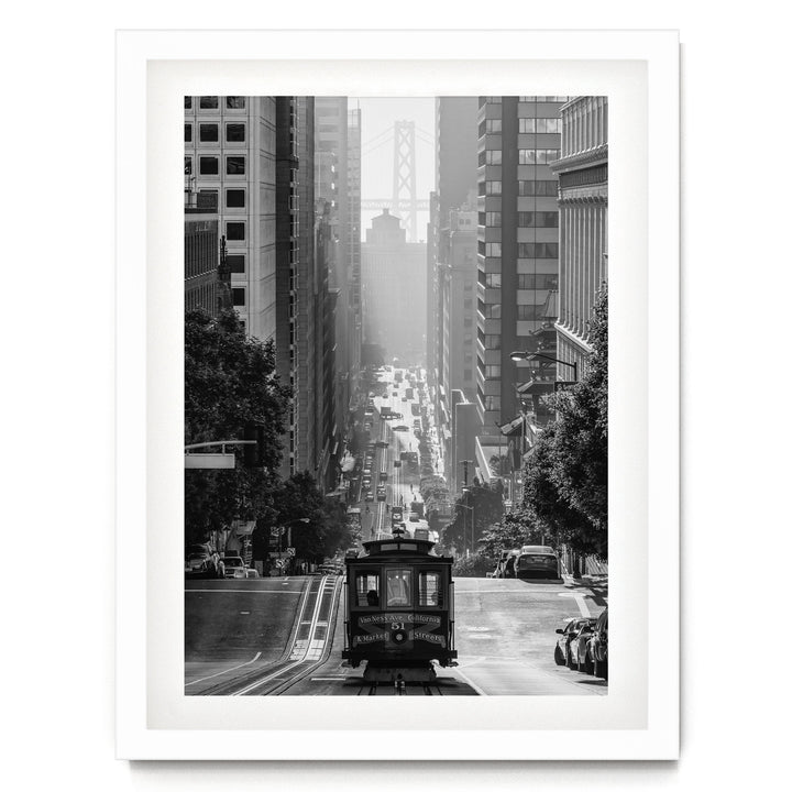 A black and white photograph of a trolley car traveling down a busy city street, surrounded by tall buildings and traffic.
