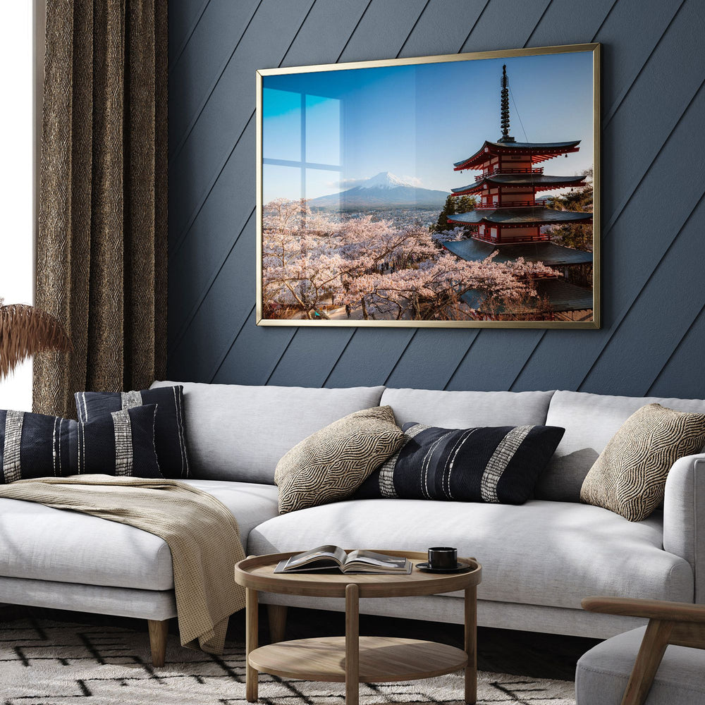 a living room with a large framed picture of a pagoda in the background, a white sofa with throw pillows, and a wooden coffee table in front of the sofa.