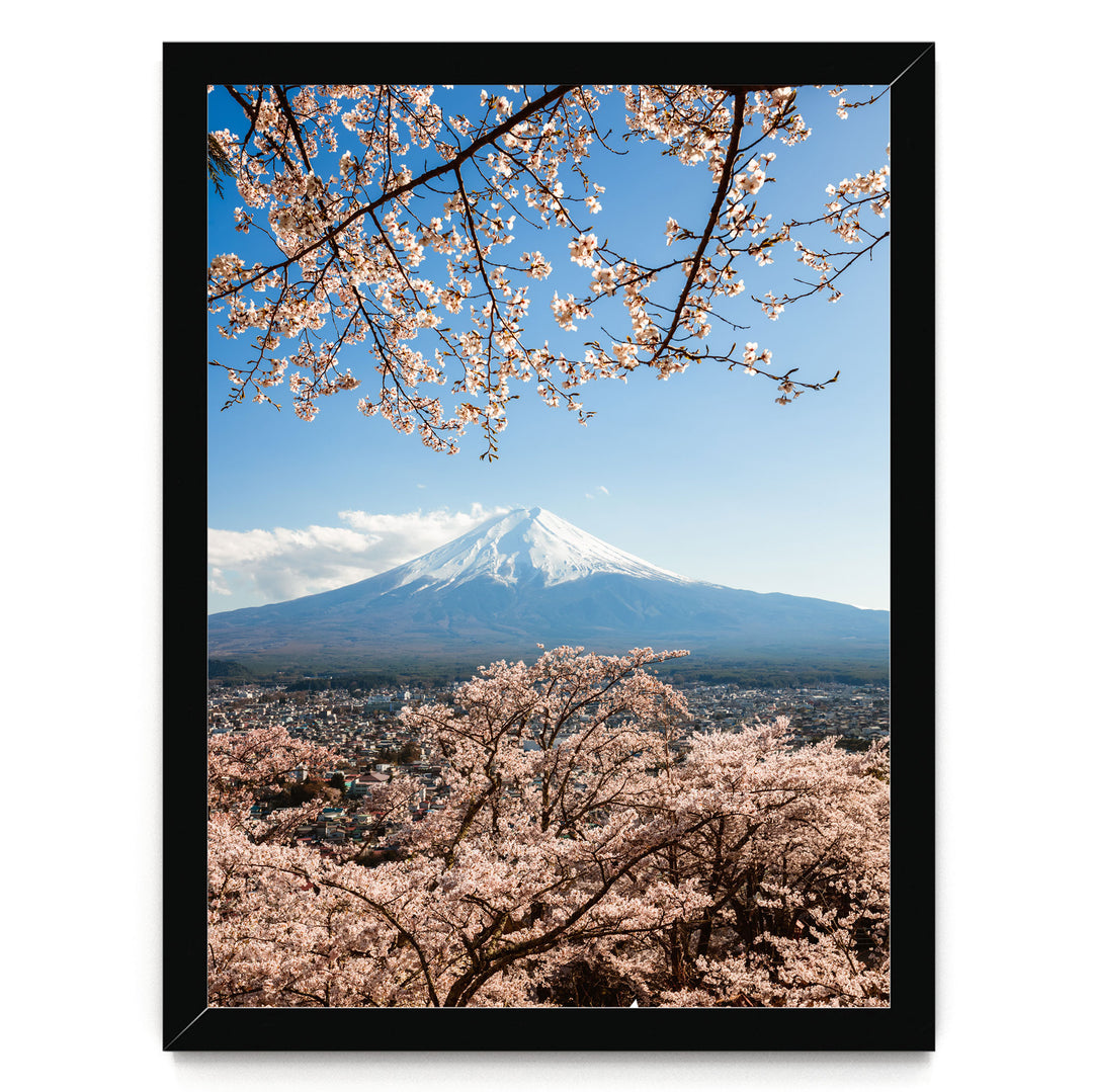 A framed photograph depicting a snow-capped mountain peak with cherry blossoms in the foreground, creating a serene and picturesque scene.
