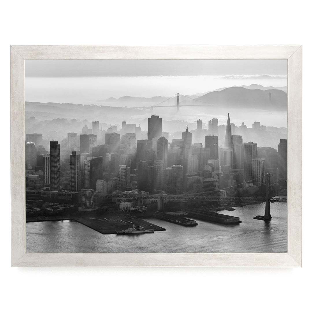 A black and white aerial view of the San Francisco skyline, with the Golden Gate Bridge and foggy cityscape in the background.