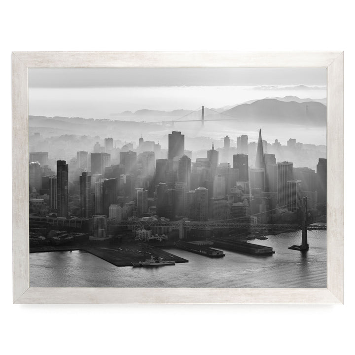 A black and white aerial view of the San Francisco skyline, with the Golden Gate Bridge and foggy cityscape in the background.