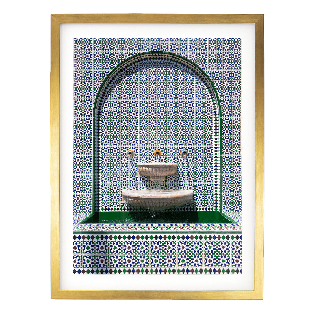 a decorative fountain with a green border and a tiled wall with a pattern of blue and white tiles.