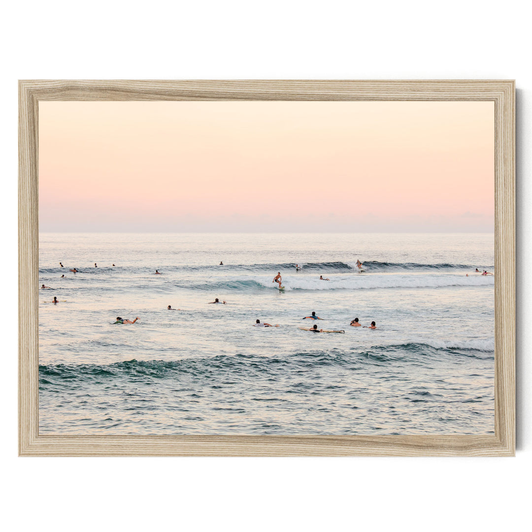 a group of people enjoying themselves in the ocean, with some swimming and others surfing on the waves.