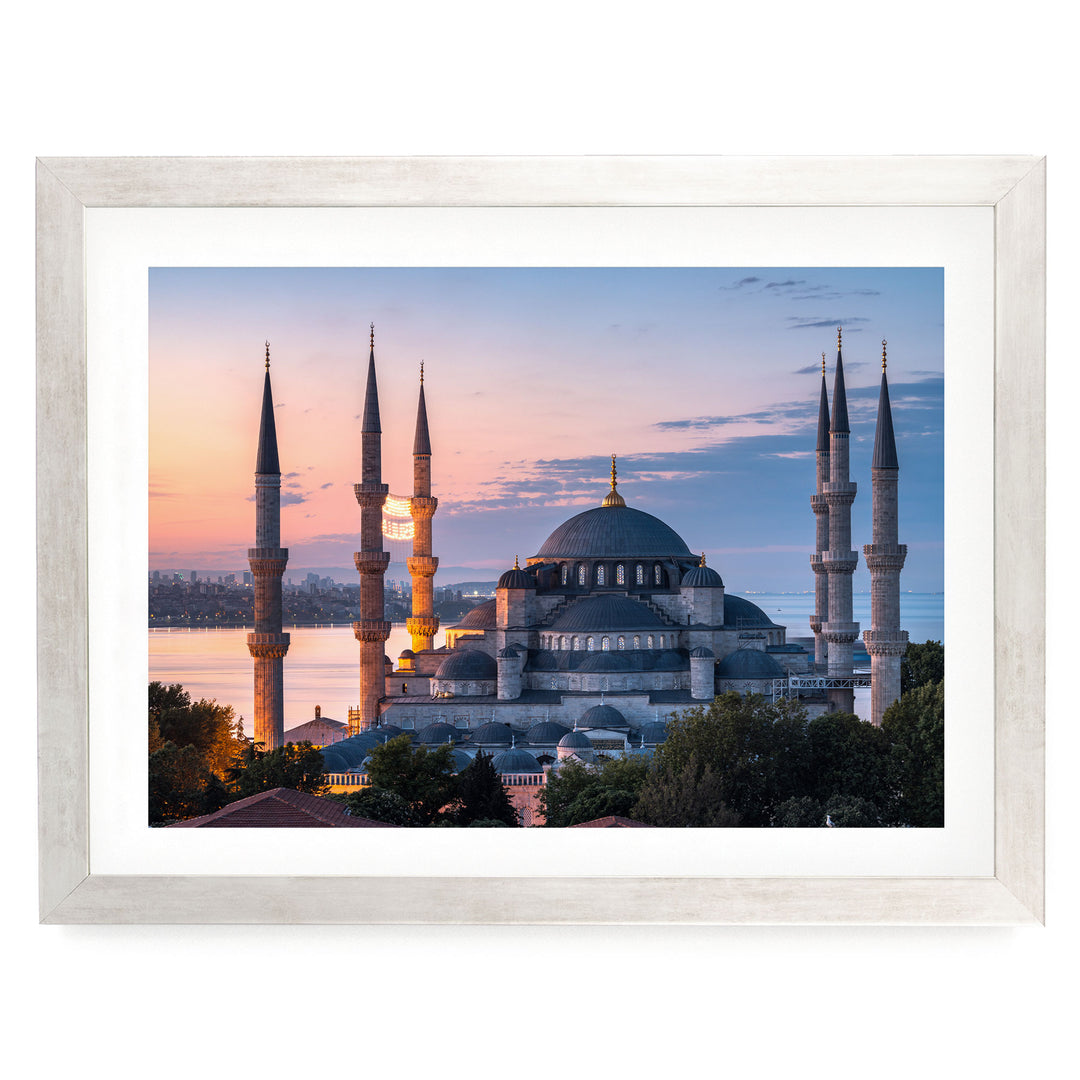 the Blue Mosque, also known as the Sultan Ahmed Mosque, in Istanbul, Turkey, with its distinctive minarets and domes silhouetted against a colorful sunset sky.