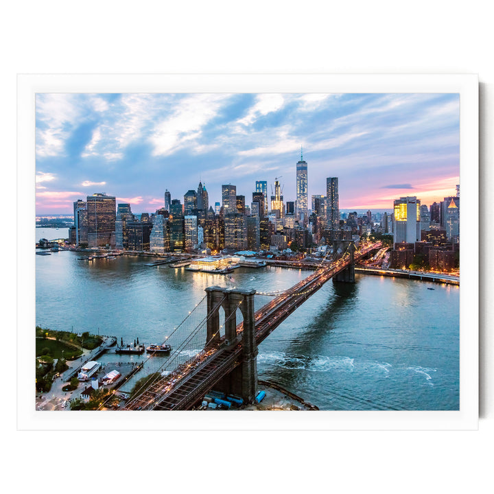 the skyline of New York City at dusk, with the Brooklyn Bridge spanning the East River in the foreground. The cityscape is illuminated by the warm glow of the setting sun, creating a vibrant and dynamic scene.