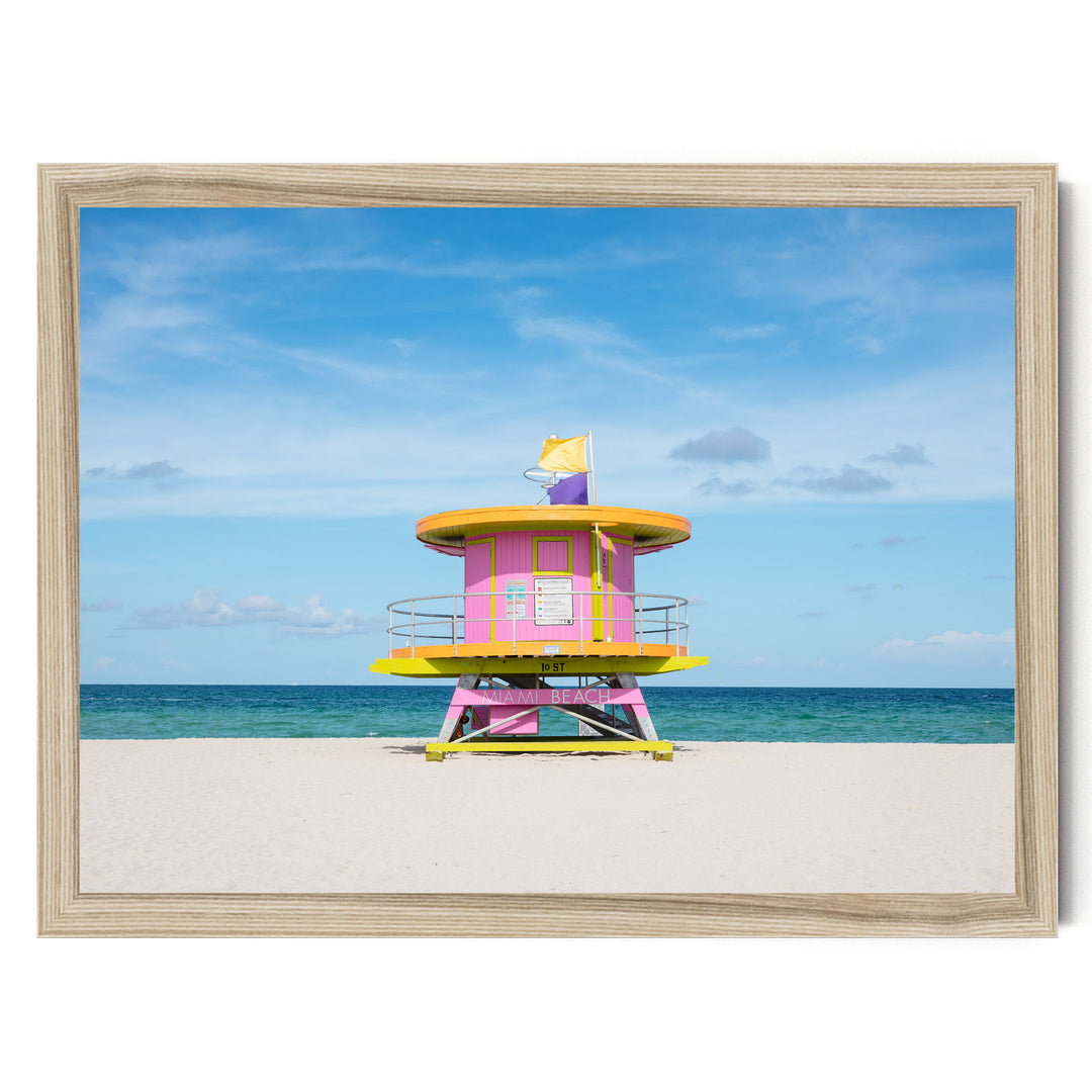 A brightly colored lifeguard tower stands on a sandy beach, with the ocean visible in the background.