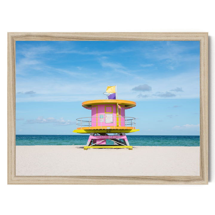 A brightly colored lifeguard tower stands on a sandy beach, with the ocean visible in the background.