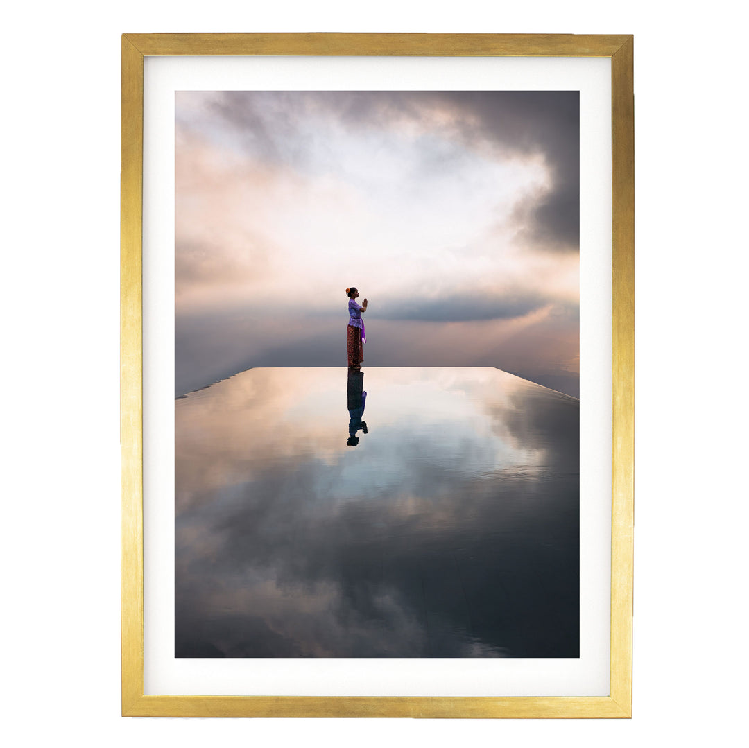 A person stands on a reflective surface, gazing out at the cloudy sky, creating a serene and contemplative scene.