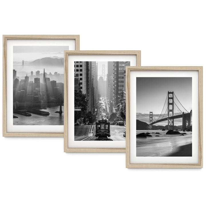three framed black and white photographs of various city scenes, including a cityscape, a trolley car, and a bridge.