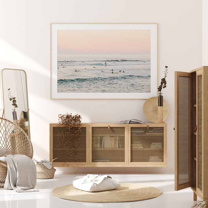 a serene and cozy living room with a large framed picture of a beach scene hanging on the wall. The room is furnished with a wooden cabinet, a woven basket, and a round rug, creating a warm and inviting atmosphere.