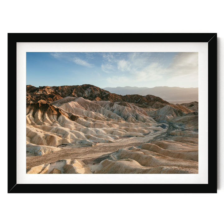 A framed photograph depicting a rugged, mountainous landscape with a clear blue sky in the background.