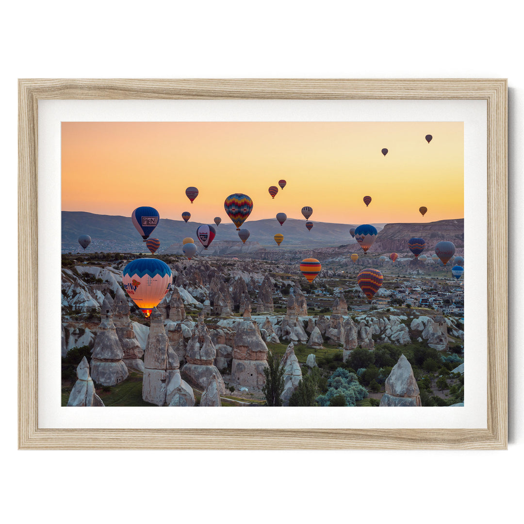 a breathtaking scene of hot air balloons floating over a mountainous landscape at sunset.