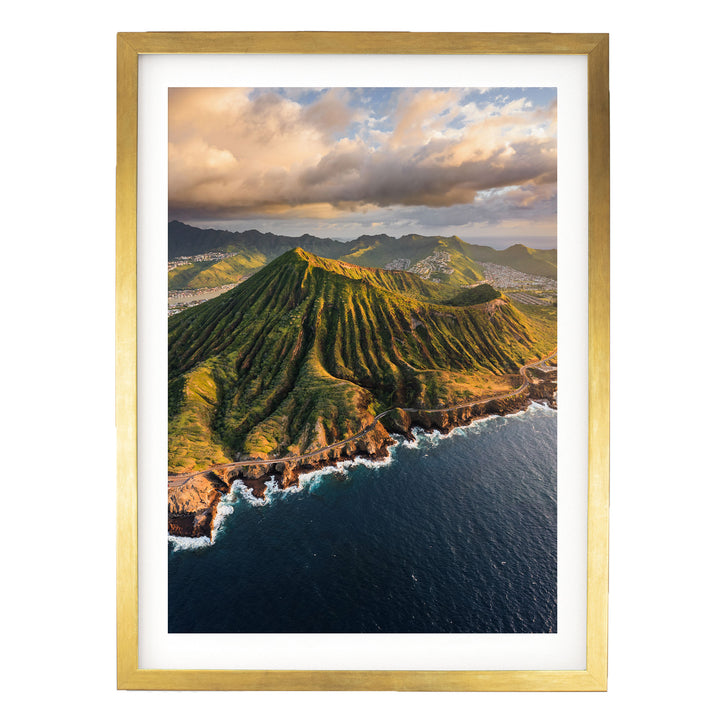 a mountainous coastline with a winding road leading to the ocean, surrounded by lush greenery and dramatic clouds in the sky.