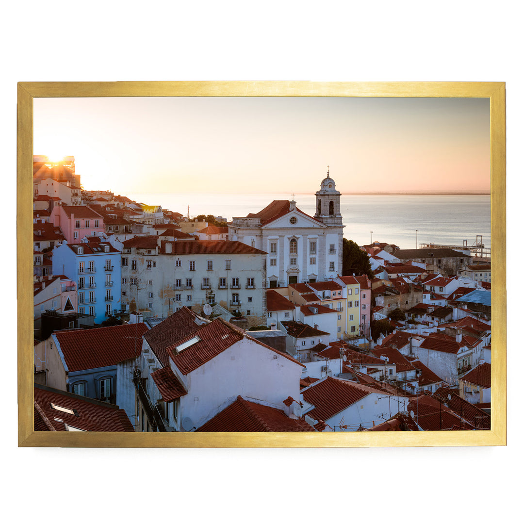 a picturesque town with a church and colorful buildings, set against a backdrop of a sunset over the ocean.
