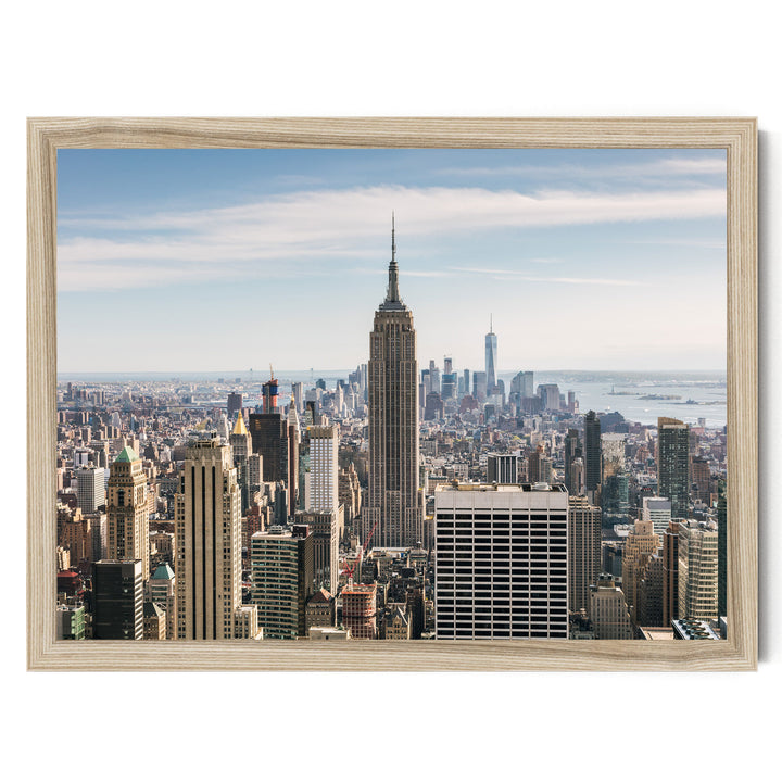 a cityscape with numerous tall buildings, including the iconic Empire State Building, set against a clear blue sky.