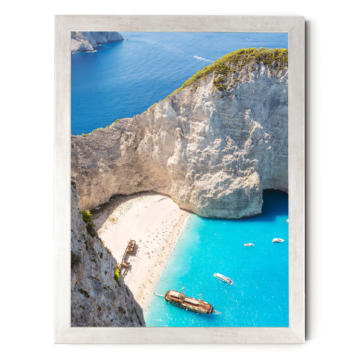a picturesque coastal scene with a rocky cliff overlooking a beach and turquoise waters. Several boats are visible in the water, adding to the serene atmosphere.