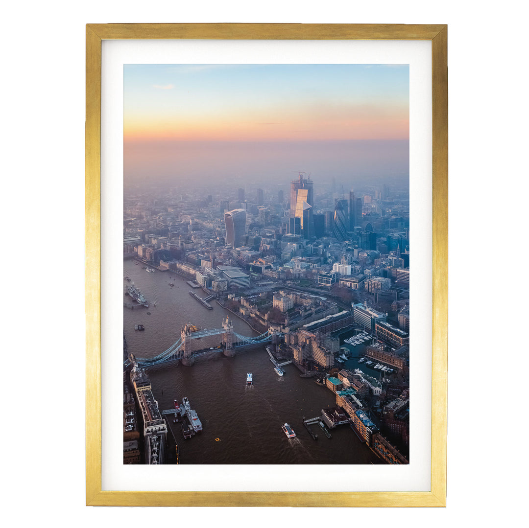 The image is an aerial view of a cityscape with a bridge, boats, and buildings, captured at sunset.