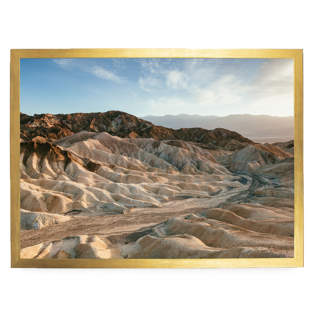 a vast, rugged landscape with rolling hills and mountains in the background, set against a clear blue sky.