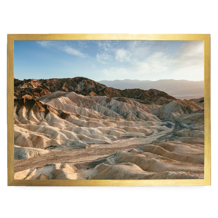 a vast, rugged landscape with rolling hills and mountains in the background, set against a clear blue sky.