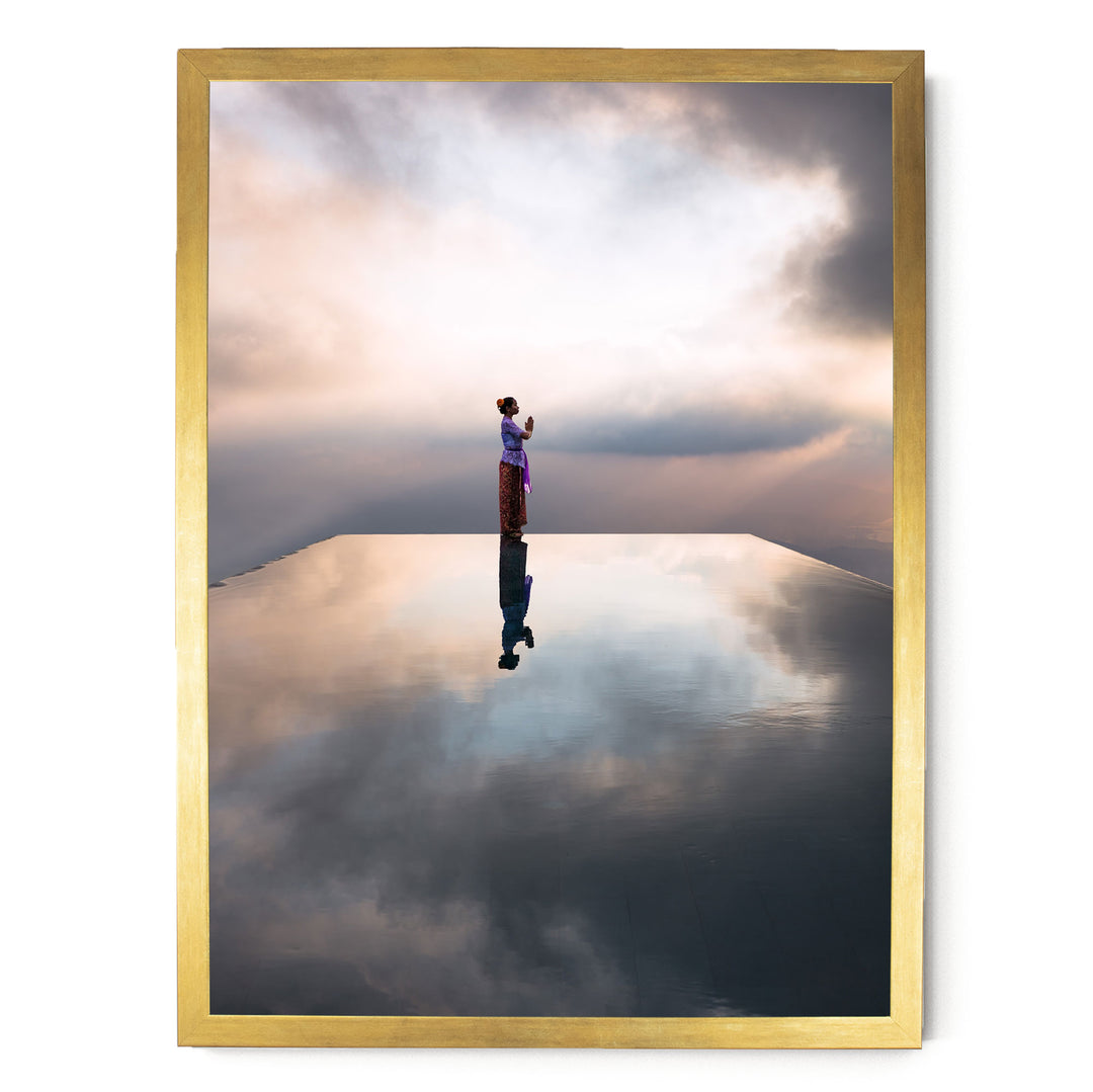A person standing on a reflective surface, possibly a pool or a mirror, with a cloudy sky in the background.
