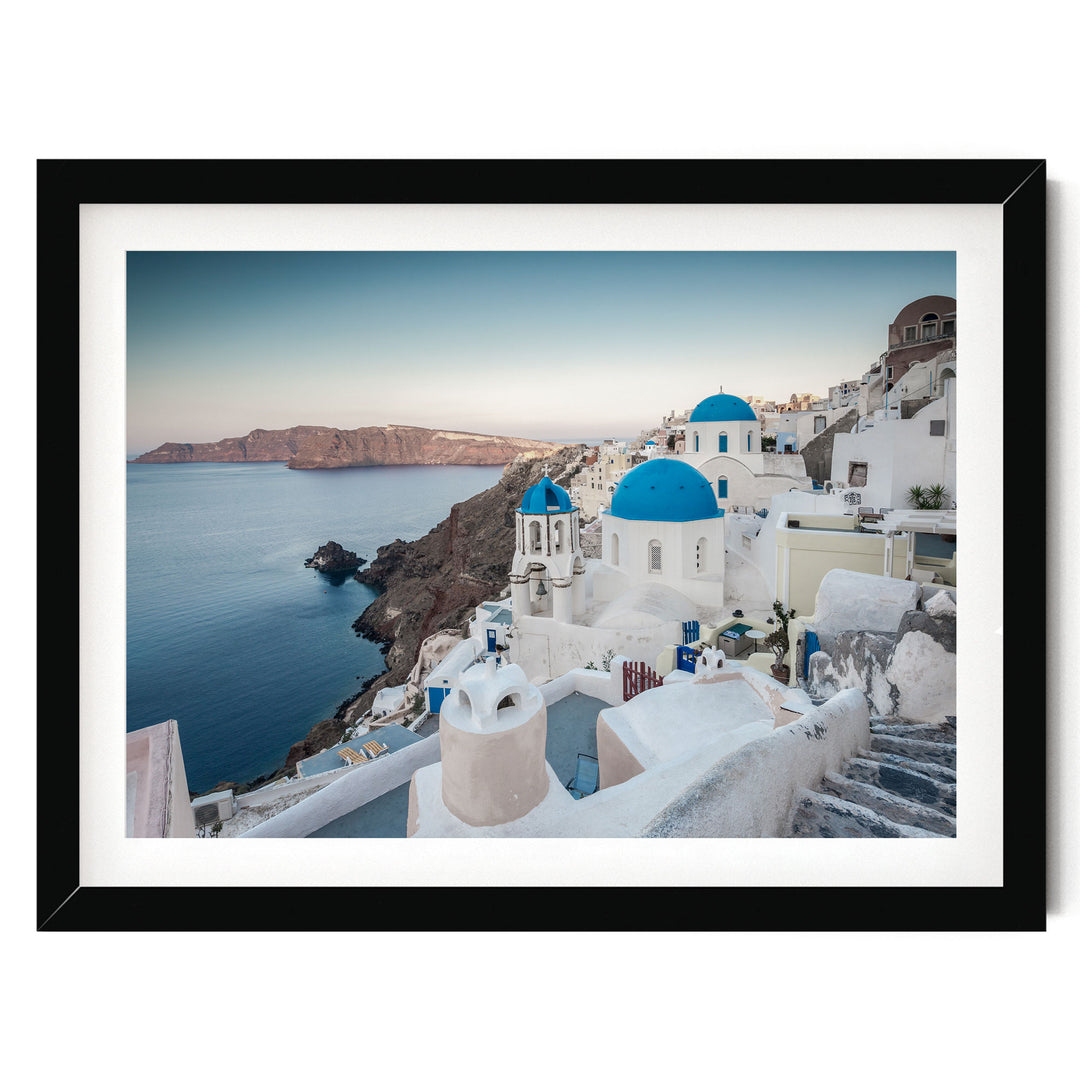 a picturesque coastal town with white buildings and blue domes, overlooking the ocean.