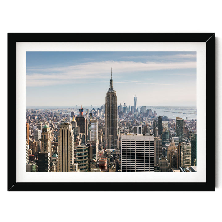 a cityscape with numerous tall buildings, including the iconic Empire State Building, set against a clear blue sky.