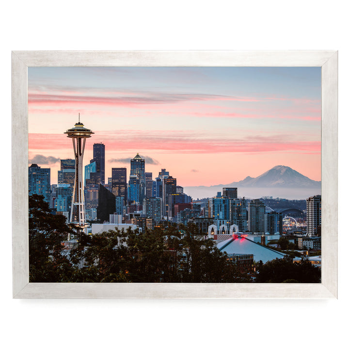 a city skyline at sunset, with the Space Needle and other high-rise buildings silhouetted against a vibrant pink and orange sky.