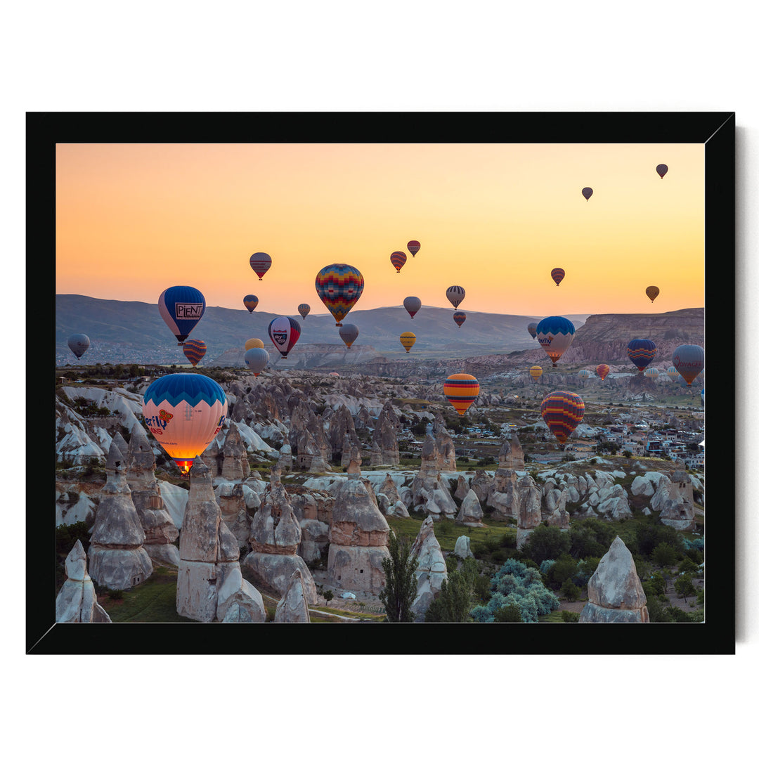 a breathtaking scene of hot air balloons floating over a mountainous landscape at sunset.