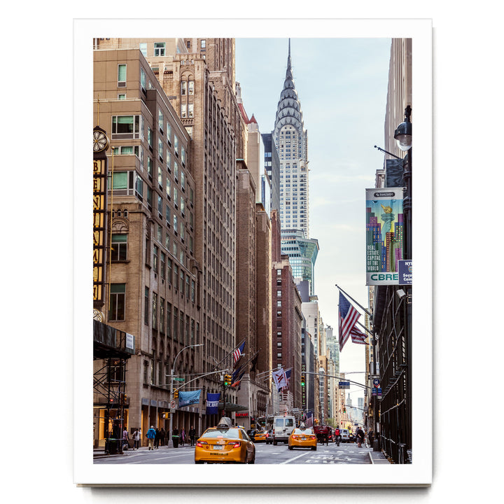 a busy city street with tall buildings, including the iconic New York City skyline, including the distinctive spire of the Chrysler Building.