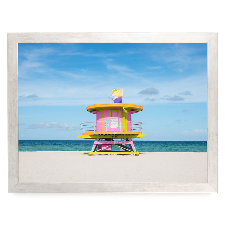 A brightly colored lifeguard tower stands on a sandy beach, overlooking the ocean.