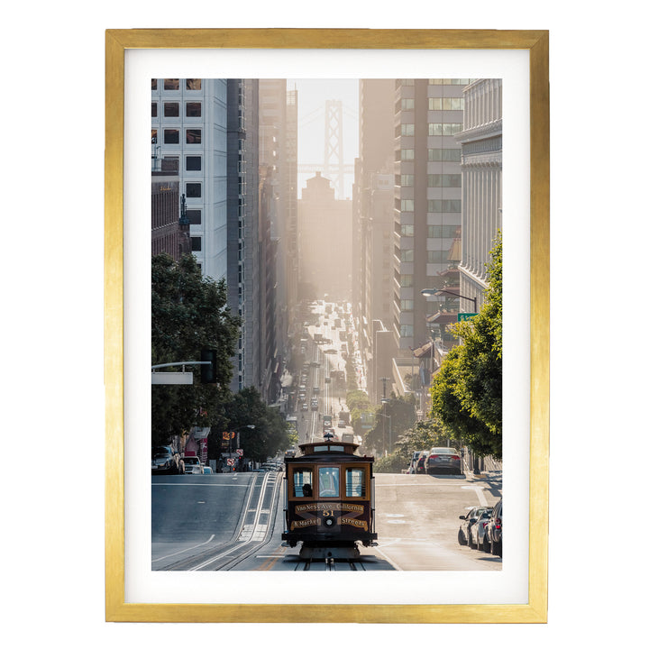 A framed photograph depicting a trolley car traveling down a city street, surrounded by tall buildings and trees.