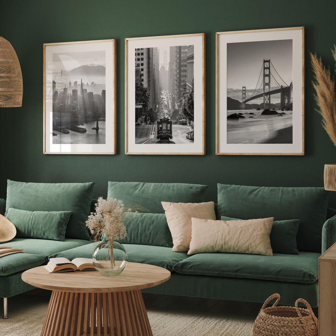 a living room with a green sofa, a wooden coffee table, and three framed black and white photographs of iconic cityscapes hanging on the wall.