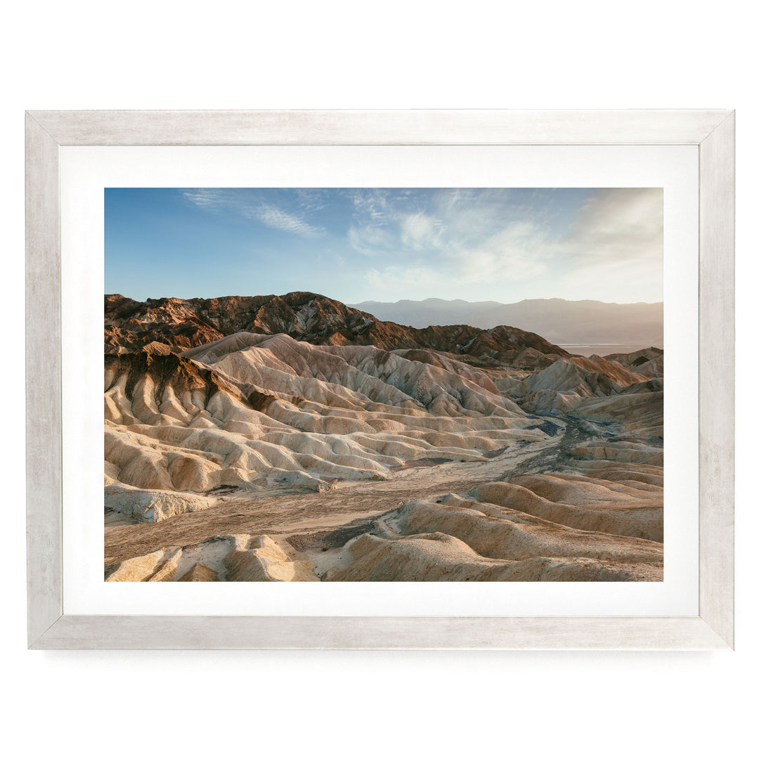 a vast, rugged landscape with rolling hills and mountains in the distance, set against a clear blue sky.
