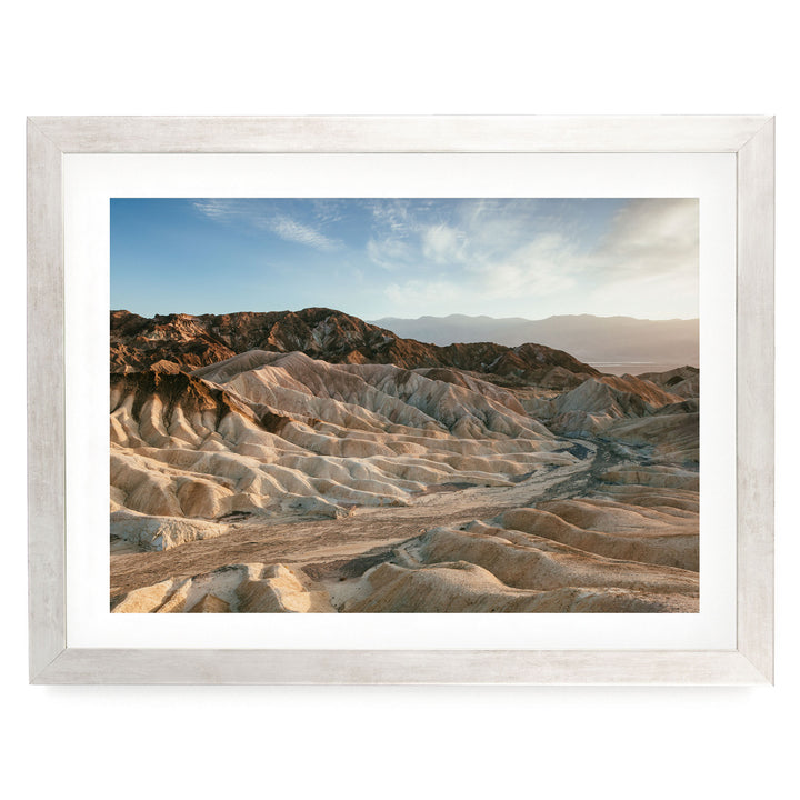 a vast, rugged landscape with rolling hills and mountains in the distance, set against a clear blue sky.