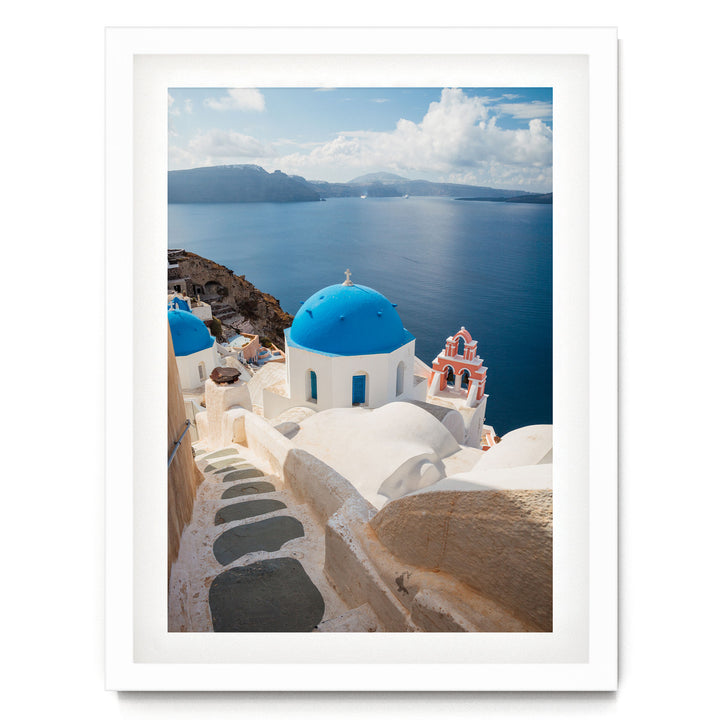 a picturesque view of a Greek island, with white buildings featuring blue domes and red roofs, overlooking the deep blue sea.