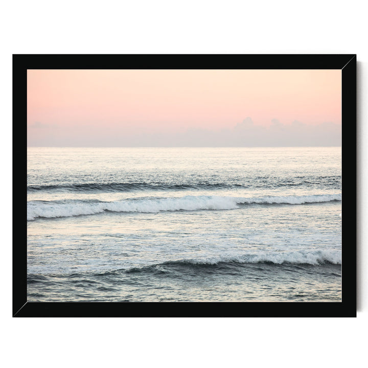 A serene ocean scene with gentle waves lapping against the shore, set against a soft pink and orange sky.