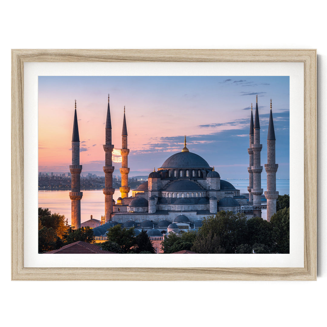 the Blue Mosque, also known as the Sultan Ahmed Mosque, in Istanbul, Turkey, with its distinctive minarets and domes silhouetted against a colorful sunset sky.